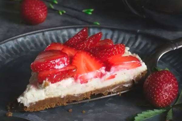 Part de tarte aux fraises sans cuisson, avec des fraises coupées sur une base crémeuse et un fond de tarte croustillant.