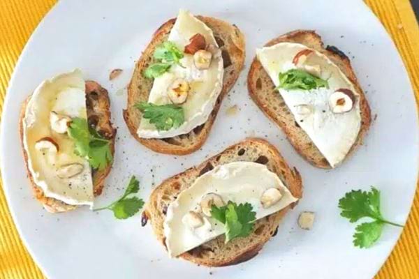 Tartines de chèvre et miel garnies de noisettes et de feuilles de coriandre.