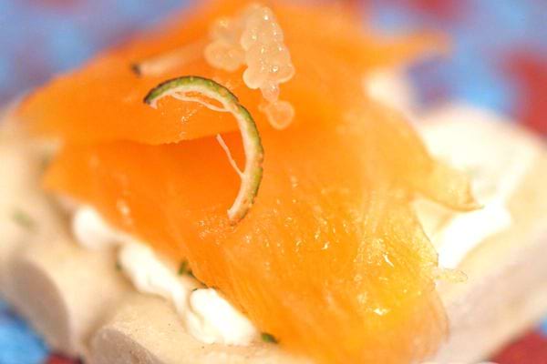 Toasts élégants avec saumon fumé, crème fraîche et caviar sur un lit de pain blanc.