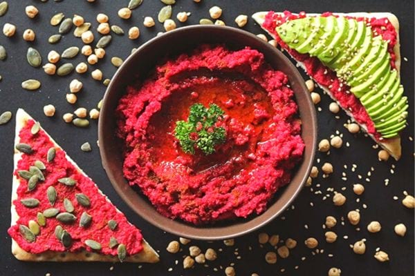 Houmous de betterave sur pain croustillant avec tranches d'avocat.