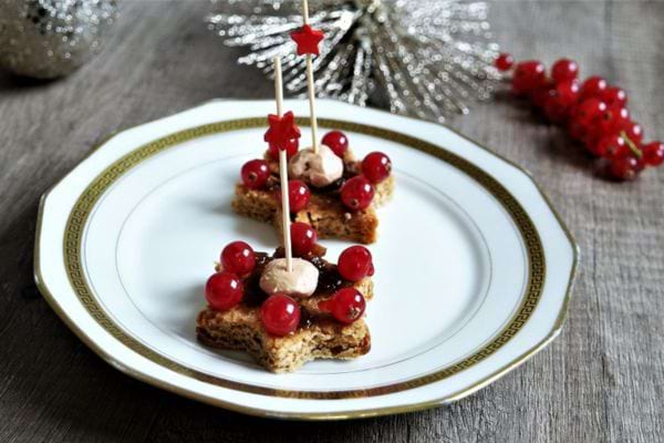 Toasts de fête avec groseilles et mousse de foie gras, décorés d'un pic étoilé.