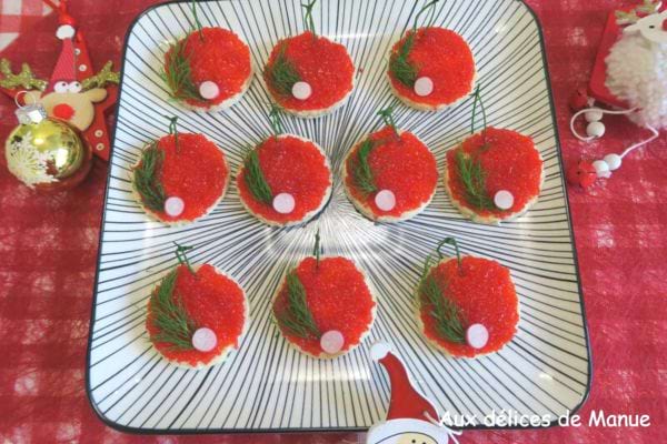 Toasts rouges au caviar d'œufs de lump et herbes, arrangés comme des boules de Noël sur une assiette festive.