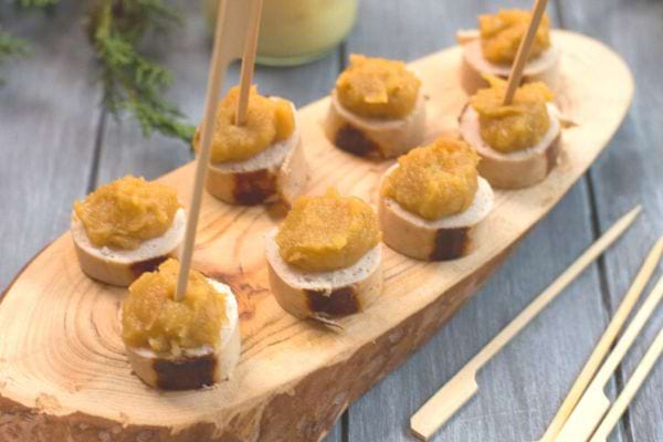 Toasts au boudin et compote de pommes, présentés sur une planche en bois rustique.