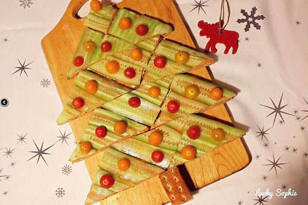 Toasts en forme de sapins de Noël décorés avec des tranches de légumes et de fromage.