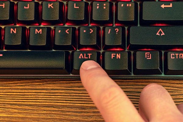 Doigt appuyant sur la touche ALT éclairée sur un clavier de gaming.