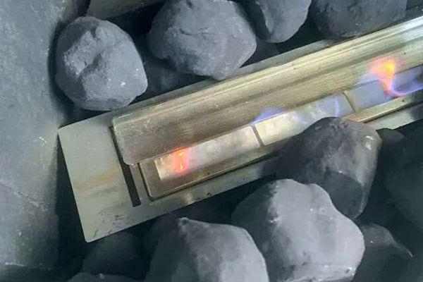 Brûleur bioéthanol inséré dans une cheminée d'apparence traditionnelle avec fausses braises.