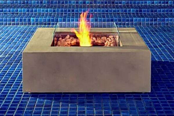 Cheminée bioéthanol sur une table près d'une piscine avec galets en céramique.