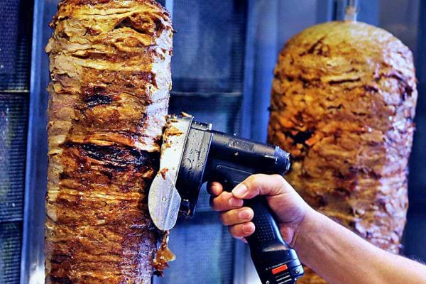 Découpe de la viande sur une broche de kebab rotative.