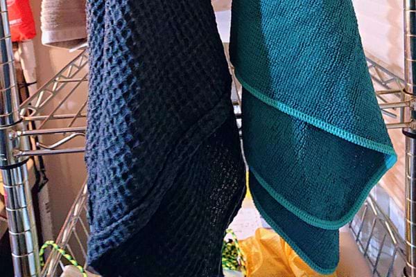 Deux serviettes de bain suspendues sur un séchoir, l'une noire et l'autre turquoise.