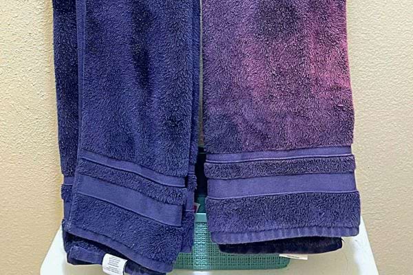 Serviettes de bain violettes avec bordures décoratives empilées sur une étagère.