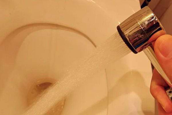 Une douchette de WC utilisée pour rincer l'intérieur d'une toilette, illustrant l'efficacité.
