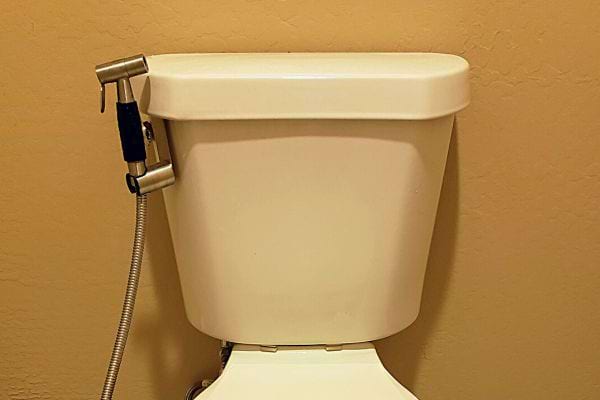 Une douchette de WC fixée à une toilette blanche, intégrée harmonieusement.