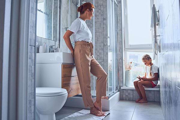 Une femme et une fille dans une salle de bain, illustrant le rôle parental dans l'enseignement de l'auto-acceptation.
