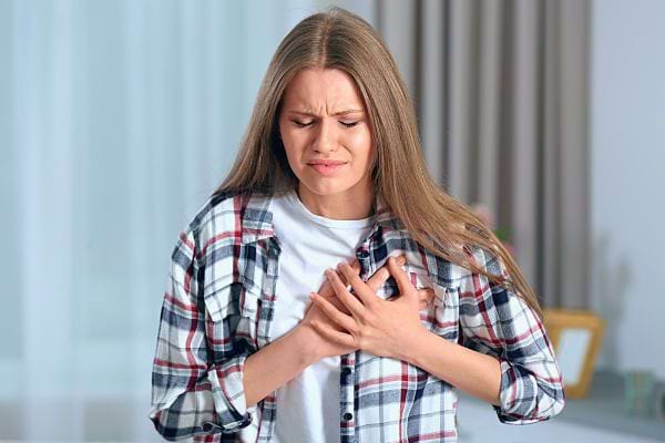 Une jeune femme en détresse, se tenant la poitrine.