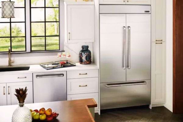 Frigo intégré dans un caisson blanc assorti aux armoires de la cuisine, offrant une unité visuelle.