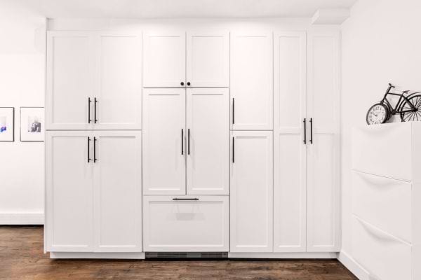 Réfrigérateur camouflé derrière des portes de placard sur mesure pour se fondre dans le décor de la cuisine.