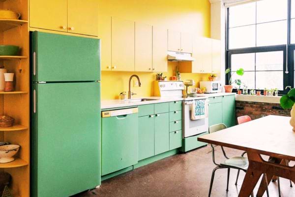 Cuisine colorée avec un frigo peint en vert pour s'harmoniser avec les armoires, ajoutant une touche de gaieté.