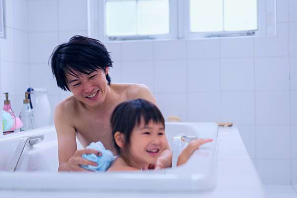 Père asiatique et sa fille rient ensemble dans une baignoire.