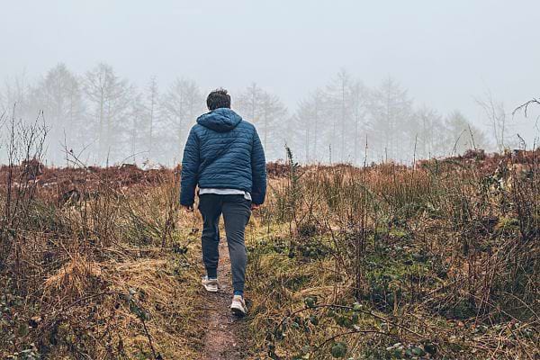 Un homme marchant seul sur un sentier en pleine nature.