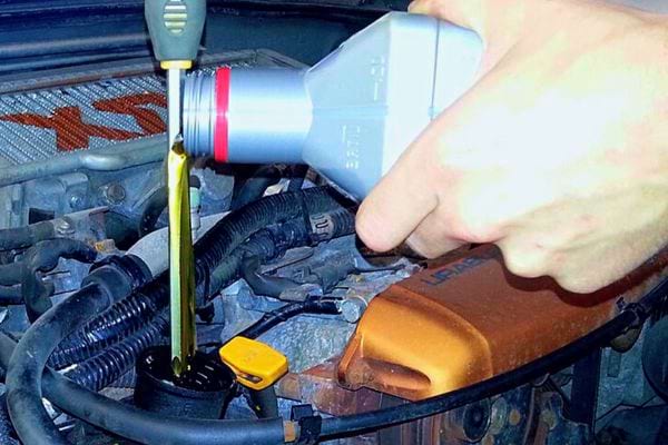 Beim Einfüllen von Motoröl in ein Fahrzeug hält man eine Dose in der Hand und gießt das Öl in den Motor.