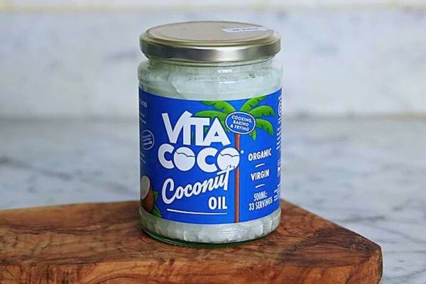 Pot de huile de noix de coco biologique sur une planche en bois.