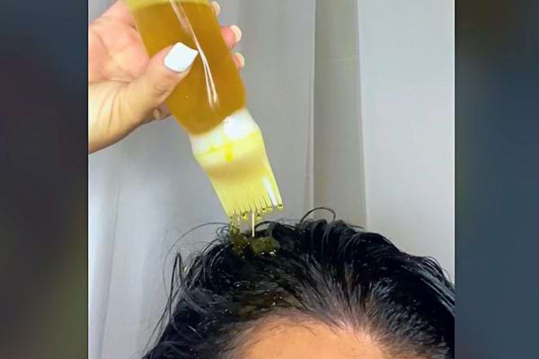 Verser de l'huile d'une bouteille avec un applicateur de brosse sur le cuir chevelu.