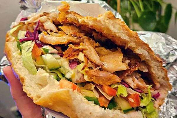 Sandwich kebab entamé dans du papier aluminium, montrant la garniture.