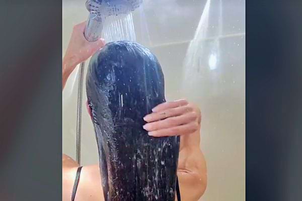 Rinçage des cheveux longs sous la douche après l'application d'huile.