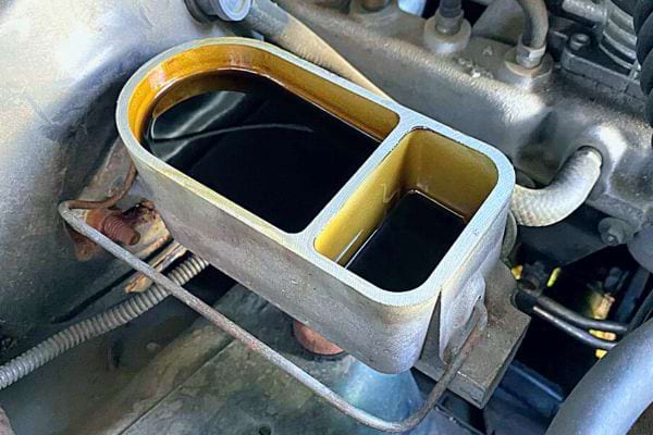 Offener Bremsflüssigkeitsbehälter in einem Automotor, dunkle Flüssigkeit zeigt an, dass ein Wechsel erforderlich ist.