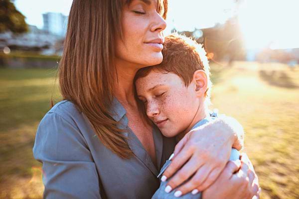 Une mère réconforte son fils dans un parc, inculquant l'empathie et le soutien familial.