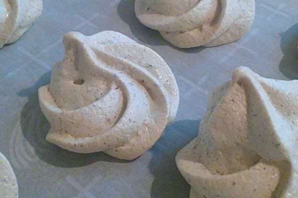 Baiser aus geschlagenem Eiweiß mit Vanilleschoten, fertig zum Backen auf Backpapier.