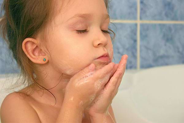 Petite fille appliquant délicatement de la mousse sur son visage.