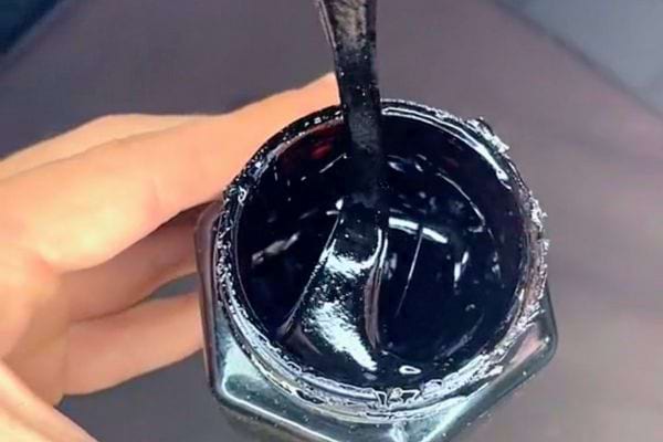 Main tenant un pot de "PureCures Himalayan Shilajit" partiellement ouvert.