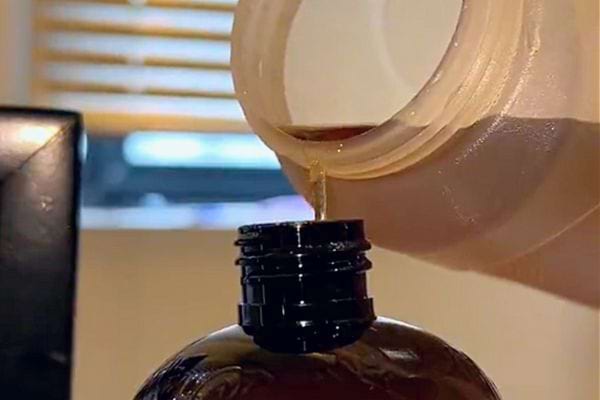 Eine bräunliche Flüssigkeit in eine dunkle Flasche gießen.