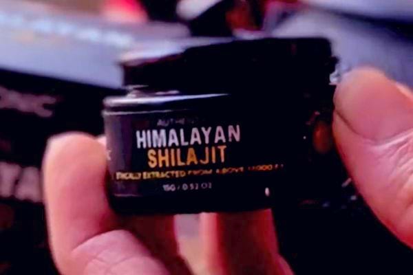 Main tenant un pot noir étiqueté "HIMALAYAN SHILAJIT".