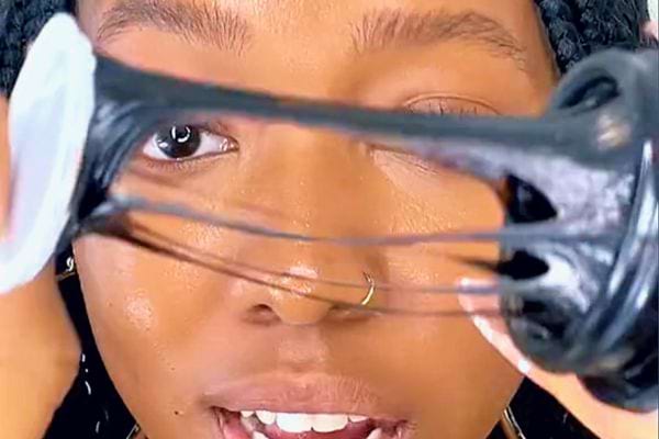 Résine de Shilajit étirée vue à travers des fouets de mixeur, devant un visage.