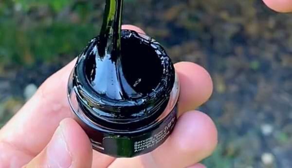 Pot de Shilajit ouvert avec résine étirée, numéroté "24" pour dosage.