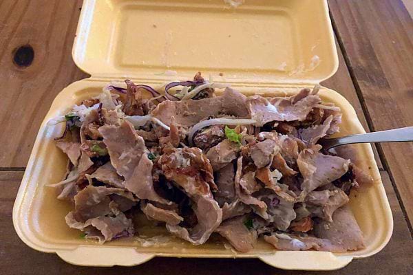 Barquette ouverte de viande de kebab émincée avec une fourchette.