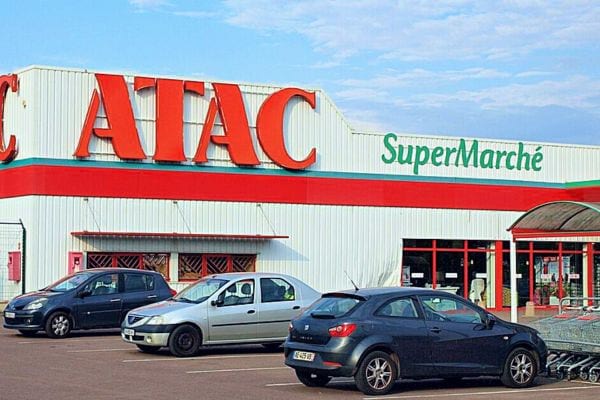 Parking du supermarché ATAC avec son enseigne rouge et le mot "SuperMarché" en vert.