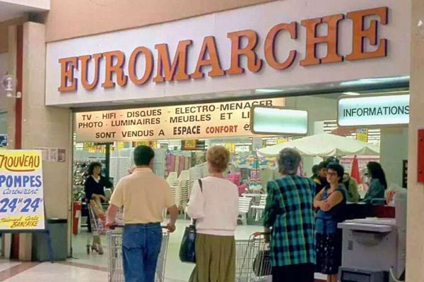 Intérieur d'un centre commercial avec l'enseigne Euromarché en orange au-dessus d'un magasin.
