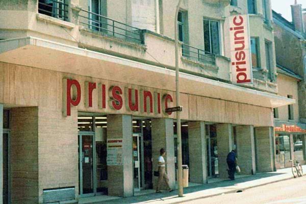 Façade d'un magasin Prisunic avec son nom en lettres capitales rouges sur un bâtiment beige.