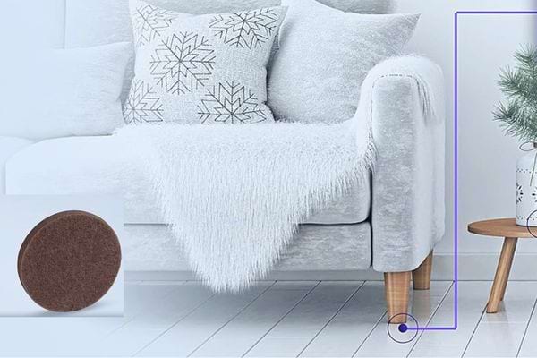 Patins en feutre sous le pied d'un canapé blanc pour le glisser sans effort.