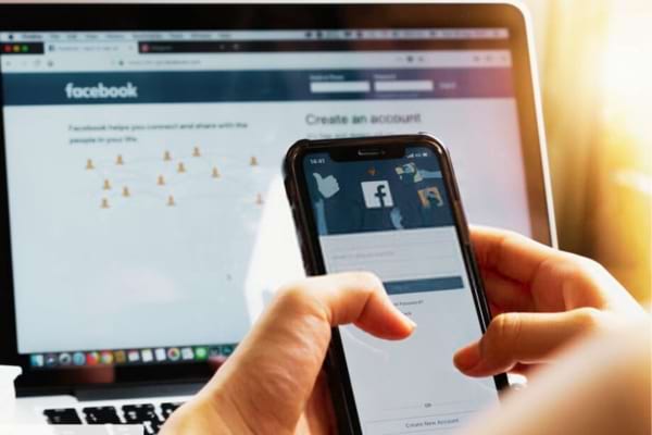 Une personne qui regarde un portable pour savoir qui consulte son profil Facebook