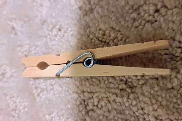 Une pince à linge en bois placée sur un tapis.