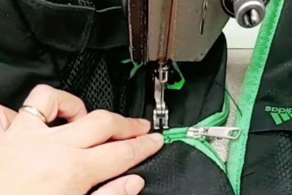 Mit einer Nähmaschine am Reißverschluss des Rucksacks festnähen