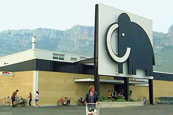 Gros plan sur le logo Mammouth, un éléphant stylisé, sur le mur extérieur d'un magasin.
