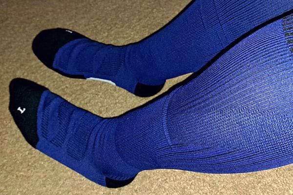 Jambes avec bas de contention bleu sur moquette.