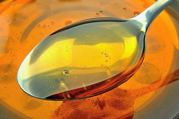 Cuillère avec du miel doré, reflétant la lumière.