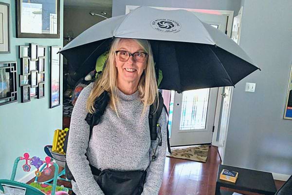 Une femme souriante sous un parapluie ouvert à l'intérieur.