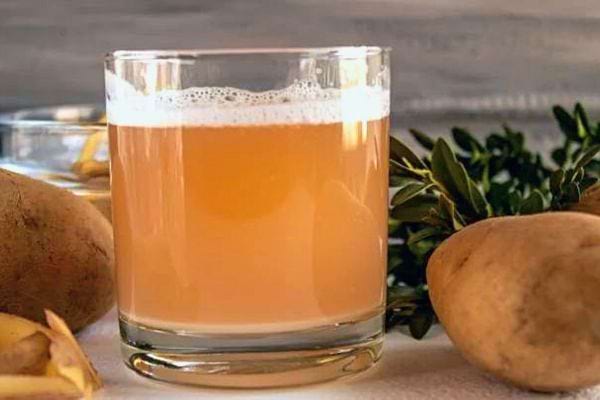 Verre de jus de pomme de terre frais avec mousse.